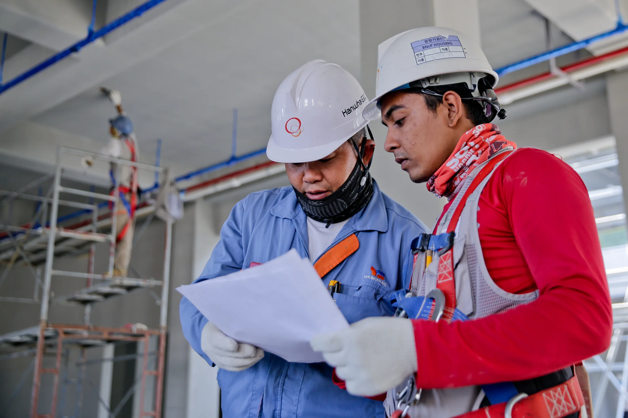 Deux employés du secteur de la construction étudient un document.